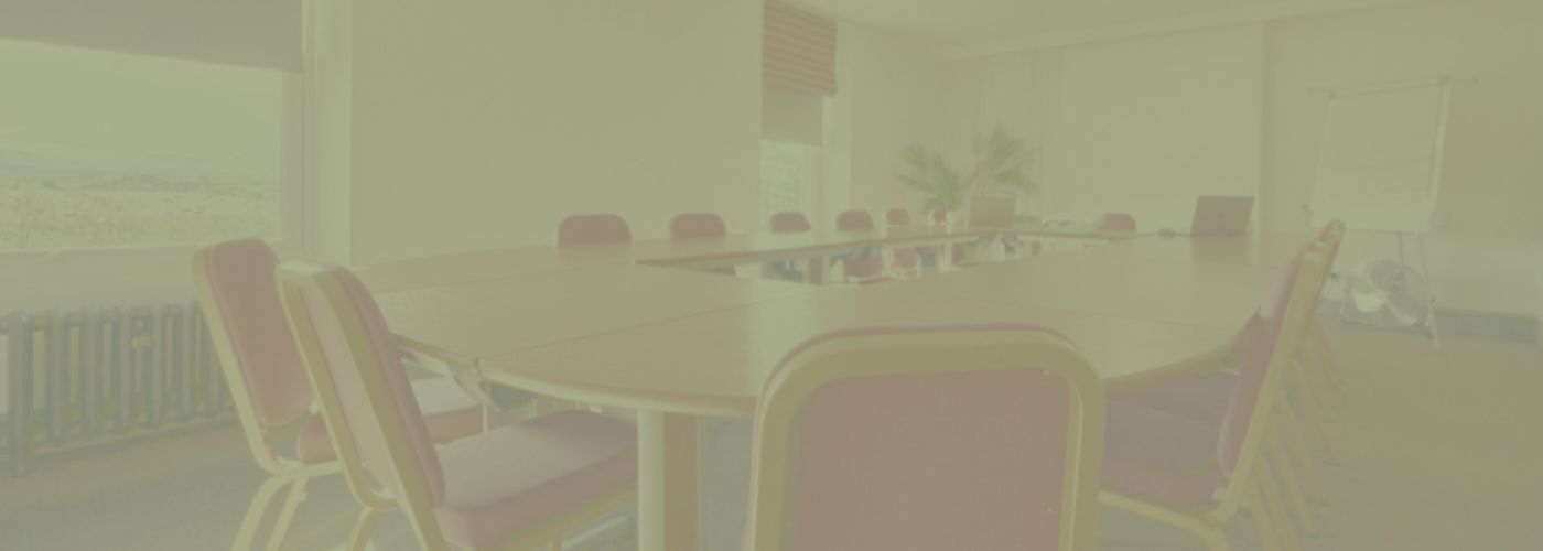 Blake Conference Room at the Melbreak, with a large conference table, projector screen and mountain views with a green background